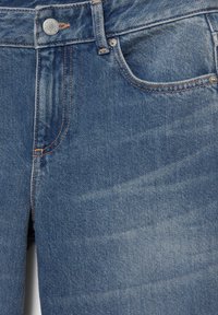 Džínsy v stredne modrej farbe s jemným vyblednutím. Majú kovový gombík, béžové švy, prednú kapsu a klasický dizajn s piatimi vreckami.