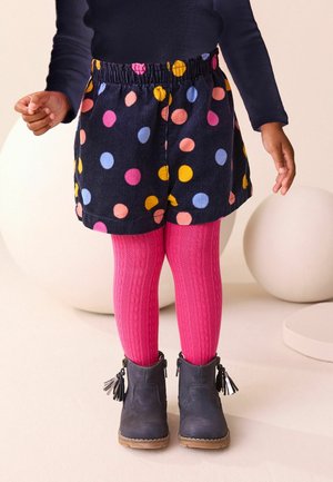Navy corduroy skirt with multicolored polka dots, paired with pink textured tights and navy boots with tassel details.