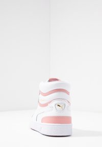 Kotníkové tenisky z bílé kůže s růžovými akcenty, texturovaným povrchem a zlatým logem na patě. Mají polstrovaný límec a gumovou podrážku.