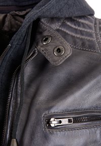 Leren jack met een antracietafwerking, voorzien van een met rits afgesloten zak, drukknoopsluitingen en een gestructureerde capuchon. Gedetailleerde stiksels in de schouderpartij.