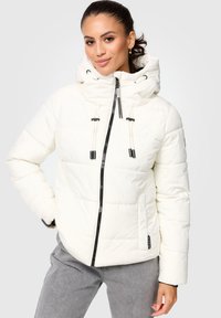 Puffer jacket, white color, quilted texture, black zipper, drawstring hood. Model wears gray pants, posing with a neutral expression.