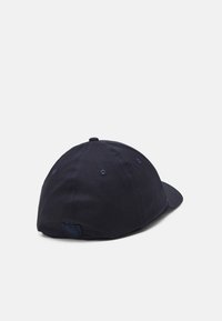 Casquette bleu marine avec une visière courbée, en coton. Comprend des trous de ventilation cousus et un petit patch logo à l'arrière.