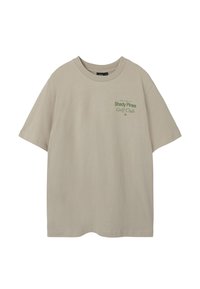 Beige katoenen t-shirt met een relaxed fit, met een groene opdruk van "Shady Pines Golf Club" op de voorkant, zonder zichtbare labels of accenten.