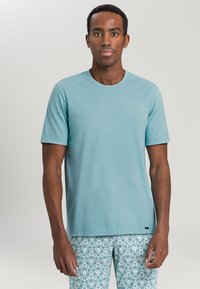 T-shirt azzurro chiaro a maniche corte realizzato in morbido tessuto di cotone, con un classico design a girocollo. Abbinato a pantaloni con motivo.