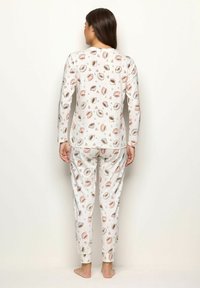 Langärmliges Schlafanzugset in Creme mit einem Kaffeetassenmuster. Weicher Stoff, lässige Passform, taillierte Hosen und elastische Bündchen an Ärmeln und Knöcheln.