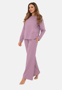 Liliowy zestaw odzieży domowej składający się z długiego rękawa topu z zaokrąglonym dołem i prostym wzorem tekstowym, w połączeniu z pasującymi szerokimi spodniami.