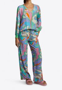 Färgglad pyjamasuppsättning bestående av en långärmad topp med V-ringning och vida byxor. Tyget har blommiga spiraler i rosa, blå, grön och orange nyanser.