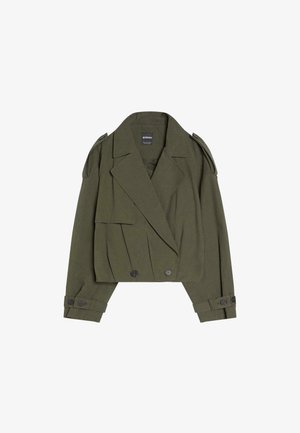 Veste courte vert olive avec fermeture croisée, larges revers, épaulettes et poignets boutonnés, en tissu texturé.