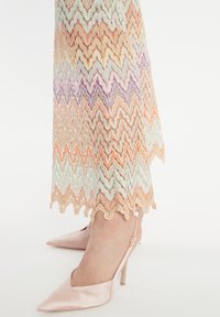 Morekleurige kanten jurk met een zigzagpatroon; kleuren zijn pastelblauw, oranje en lavendel. Gecombineerd met een lichtroze satijnen hak.