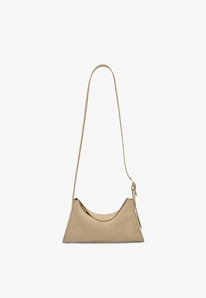 Bolso de hombro beige de ante con una correa larga y un diseño minimalista, con una forma suave y caída y detalle de borla lateral.