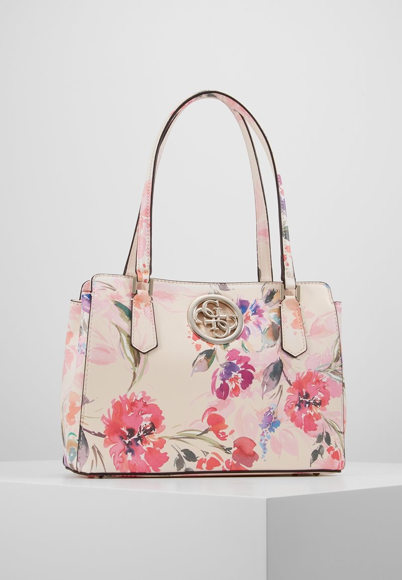 Blommig tote-väska i mjuk rosa material med krämig bakgrund, prydd med färgglada blommor, dubbla handtag och en cirkulär logotyp på framsidan.