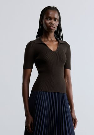 Top marrone a maniche corte a coste con colletto, caratterizzato da un design a scollo a V. Abbinato a una gonna plissettata blu navy per un look stratificato.