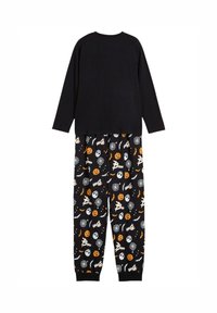 Maglietta nera a maniche lunghe abbinata a pantaloni del pigiama neri con motivi a tema Halloween in arancione e bianco, tra cui zucche e fantasmi.
