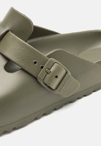 Infradito impermeabili di colore verde oliva con finitura testurizzata, cinturino regolabile con fibbia e soletta sagomata per il comfort.