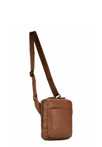 Sac à bandoulière en cuir marron avec un compartiment principal zippé, une poche avant et une sangle en tissu réglable. Texture lisse, forme rectangulaire.