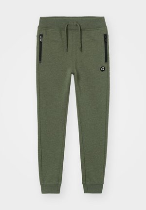 Pantalon de jogging vert foncé avec poignets élastiques, ceinture à cordon, deux poches latérales noires zippées et un petit logo rond sur la cuisse droite.