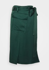 Grön tygkjol med en sidoklyfta, utrustad med en stor lapplomme och ett knytbälte. Slät yta med kontrasterande sömmar.