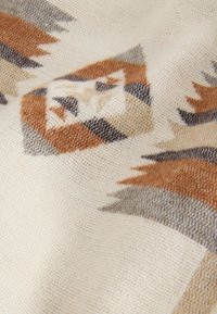 Tissu tissé avec une base crème, présentant des motifs géométriques en tons orange, marron et gris ; texture douce avec une finition lisse.