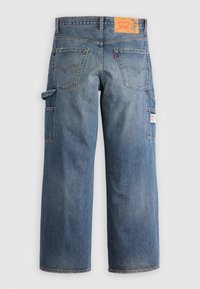 Pantalones cargo de mezclilla en un lavado azul claro. Presenta dos bolsillos traseros, un bolsillo lateral y una etiqueta grande en la cintura. Corte holgado, pierna recta.