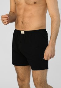 Černé bavlněné boxerky s elastickým pasem, mají přední knoflíkovou uzávěr a štítek na pasu. Jemná textura, ležérní design.