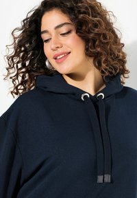 Felpa con cappuccio blu navy in cotone, dotata di un cordino con accentuazioni metalliche, dalla vestibilità rilassata e dalla texture morbida.