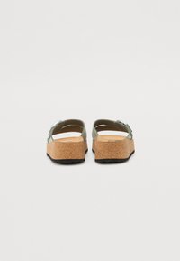 Groene platformsandalen met een kurken zool, voorzien van twee verstelbare banden en een metalen gesp. Vriendelijke textuur en brede teenruimte.