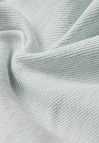 Ljust blått texturerat tyg med diagonalt ribbat mönster, som visar en mjuk, något ludden yta och en lätt drapering.