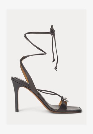 Black leather high-heeled sandal with thin straps, ankle wrap ties, square toe, and silver double ring decoration on front strap.