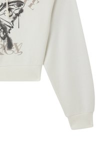 Skórzana kremowa bluza z długimi rękawami, z czarnym i szarym motywem motyla oraz stylizowanym tekstem z przodu.