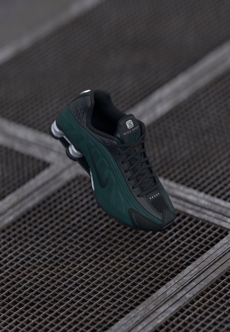 Sapatilhas Nike em preto e verde escuro com uma superfície texturizada. As características incluem um cabedal em malha, cordões proeminentes e um acolchoamento distinto no calcanhar.