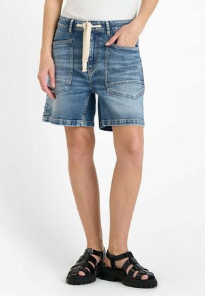 Shorts en denim bleu clair avec une coupe décontractée, comportant deux poches avant, une taille élastique avec cordon de serrage, et un ourlet effiloché. Portés avec des sandales noires.