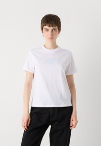 White cotton t-shirt with short sleeves and a crew neckline. Features a light blue Calvin Klein logo centered on the chest.