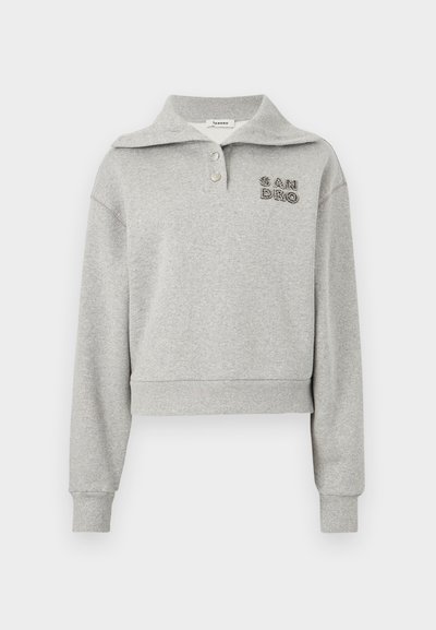 Világosszürke, hosszú ujjú pulóver széles gallérral, két gombbal, bordázott mandzsettákkal és szegéllyel, valamint a "SANDRO" hímzéssel a bal mellrészen.