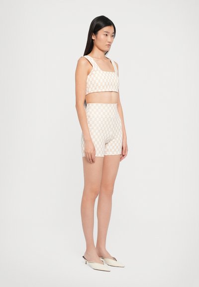 Ljus beige bh- och shorts-set med rutig mönstring, tunna axelremmar och hög midja. Materialet är slätt och åtsittande.