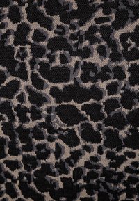 Svart och beige tyg med leopardmönster; har oregelbundna fläckar och en slät textur. Tyg som är sträckt och vävt med lyster.