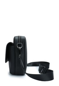 Black leather bag with a structured design, featuring a zip closure, adjustable strap, and textured surface. Small front flap detail.