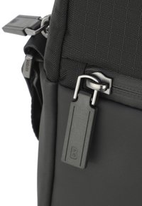 Čierna taška z textilného materiálu s textúrovaným nylonovým povrchom, hladkými koženými akcentmi, striebornými kovovými doplnkami a výraznou čiernou visačkou s embosovaným 'B'.