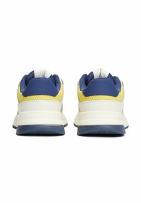 Białe i granatowe sneakersy z żółtymi akcentami, teksturowany materiał, zaokrąglony kształt, wyścielony kołnierz oraz logo na pięcie.