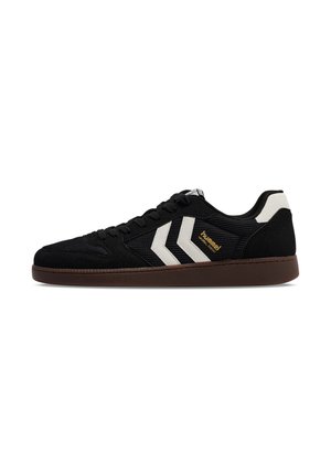 Schwarzer Low-Top-Sneaker mit brauner Sohle, weißen Chevron-Streifen an der Seite und goldenem "hummel" Schriftzug.