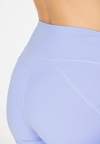 Ljust lila högmidjade leggings med mjuk och elastisk tyg. Har platta sömmar och subtila texturerade detaljer vid midjan.