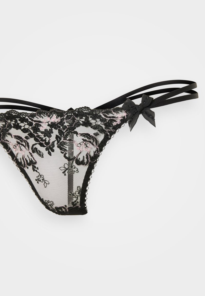 Perizoma in pizzo nero con ricami floreali in rosa e grigio, dotato di fascette nere e dettagli a fiocco, realizzato in tessuto in rete semi-trasparente.