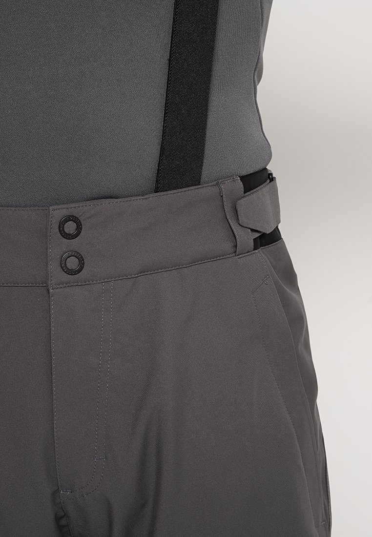 Szare spodnie z regulowanym paskiem w talii. Posiadają dwa okrągłe guziki oraz zaczepy na szelki. Materiał jest gładki o matowej fakturze.