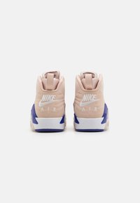 Nike Air sneakers z miękkim różowym cholewką, białym logo, niebieskimi akcentami, zaokrąglonym kształtem i amortyzowanym designem pięty.