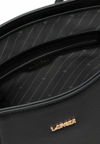 Interno di una borsa nera in pelle con una tasca con cerniera, un'etichetta con il logo e una fodera decorata con sottili strisce grigie.