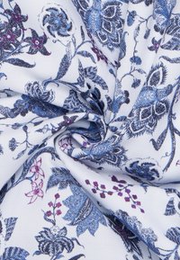 Tessuto di cotone con un motivo floreale blu e viola su sfondo bianco, con dettagli intricati e una consistenza morbida.