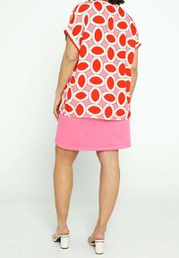 Rød- og hvidmønstret top med en lyserød nederdel, der har en løs pasform, korte ærmer og blokfarvedesign. Bæres med hvide hæleede sandaler.