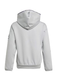 Haut à capuche gris clair présentant un tissu texturé, une capuche avec cordon de serrage, un ourlet et des poignets côtelés, ainsi qu'un logo circulaire sur la manche gauche.