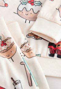 Fleece fabric with playful illustrations of desserts and snacks in soft colors. Features ribbed cuffs, with light background and diverse patterns.