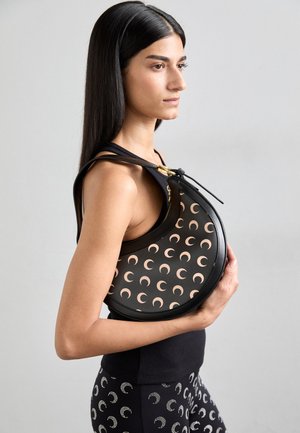 Round black leather bag with a pattern of crescent shapes in light pink. Features a gold zipper and drawstring closure, carried against the body.