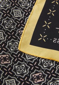 Foulard carré avec une base noire ornée d'un motif géométrique en crème, rose et jaune. Encadré d'une bordure jaune et avec des bords cousus.
